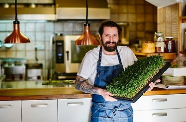 Chef Pavel Drdel at the Sůl & řepa restaurant holding tray with microgreens.