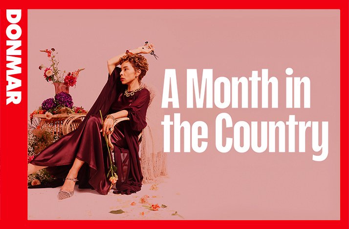 Sophie Okonedo posed with blooms and scissors in a burgundy dress beside bold white title text 'A Month in the Country' at the Donmar Warehouse.