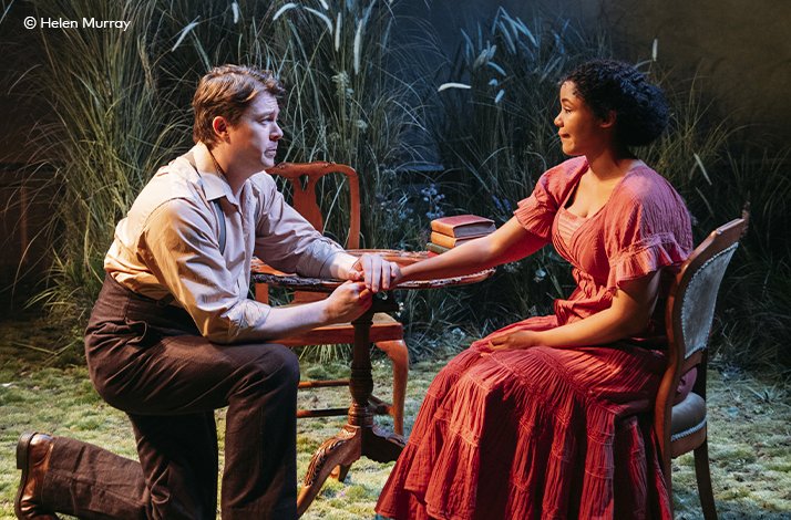 Two cast members sharing an intimate, emotionally charged moment, hands clasped across a table, in 'A Month in the Country' at the Donmar Warehouse. © Helen Murray.