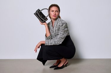 A sitting woman model, promoting Answear hand purse and clothing.