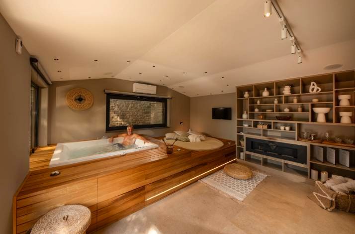 Person relaxing in a wood-framed indoor jacuzzi inside a serene wellness suite at Polidor Camping Resort, Istria.