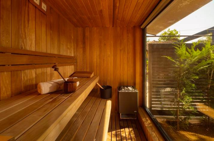 Sun-drenched cedar sauna interior with wooden benches, sauna stones and garden view at Polidor Camping Resort, Poreč.