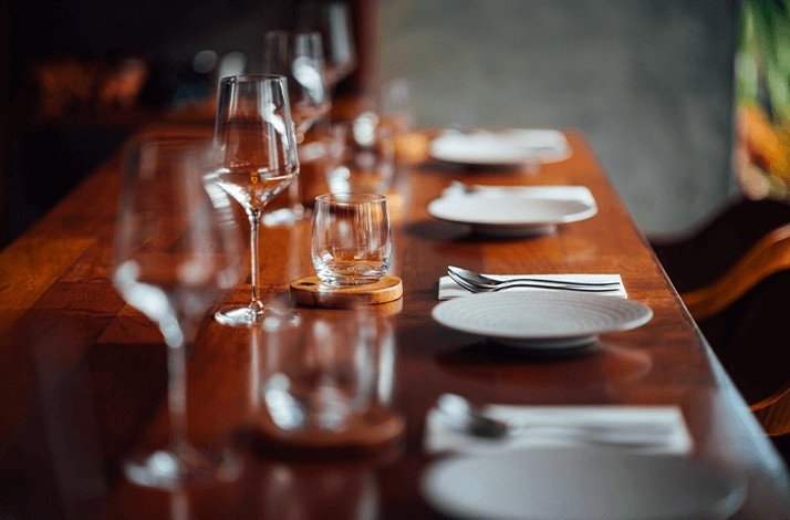 Close shot of communal table with plates and wine glasses.