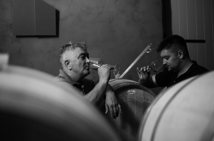 Black and white photo of two men  tasting wine in a wine cellar.
