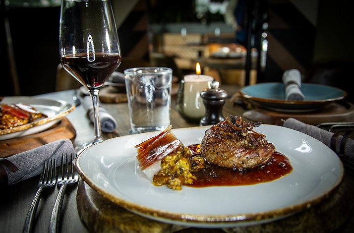 A close shot of a freshly prepared meat in Cachava steakhouse, paired with wine