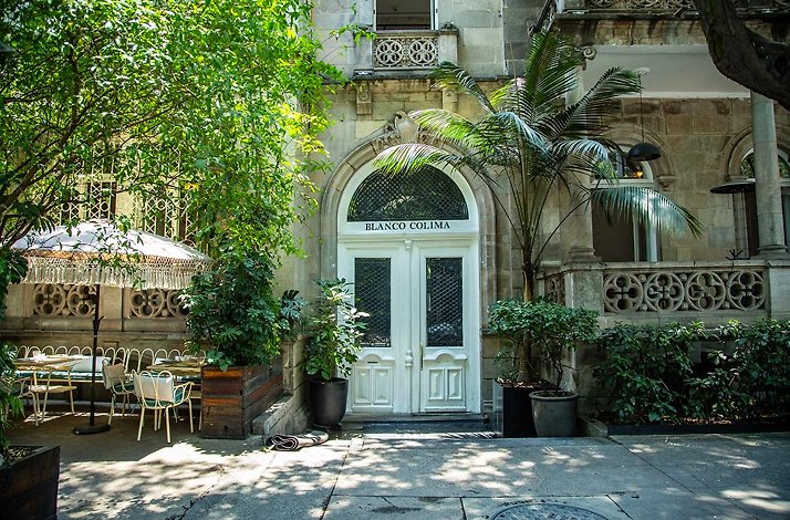 Outdoowr dining area next to the white entrance door of Blanco Colima.