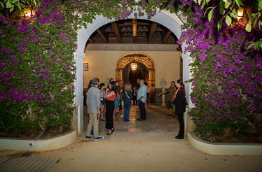 A beautiful floral arch at Palacio de las Dueñas. People in a guided tour can be seen through the arch