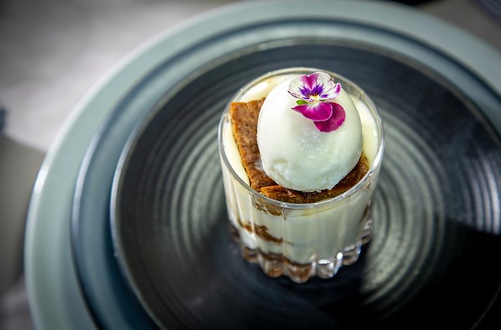 Dessert dish with ice cream topping and decorated with a violet.