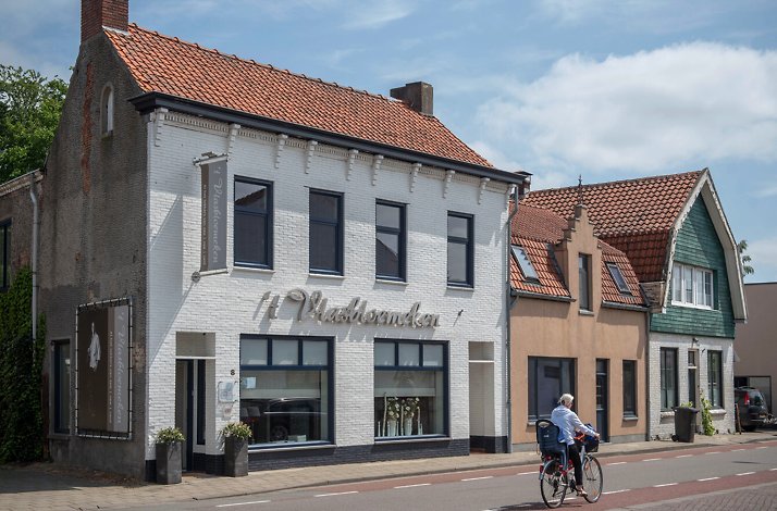 Facade of the 't Vlasbloemeken restaurant. Woman is riding past the restaurant on a bicycle.