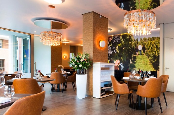 The interior of restaurant decorated with flowers in mild pastel colours with a grape farm wallpaper at the distant wall 