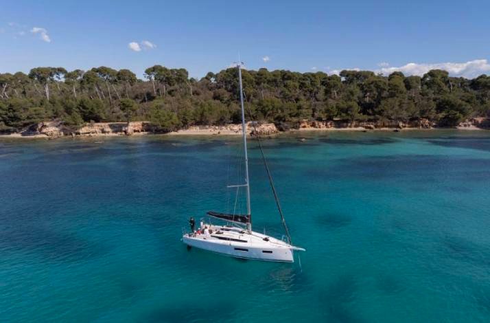 A sailboat gliding across clear blue water under a bright sky.