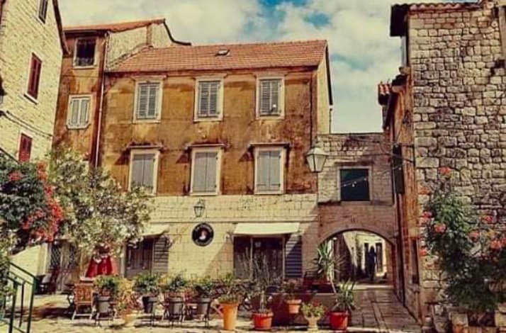 An image showcasing a yard surrounded by old buildings and greenery in the UNESCO World Heritage city, Stari Grad.