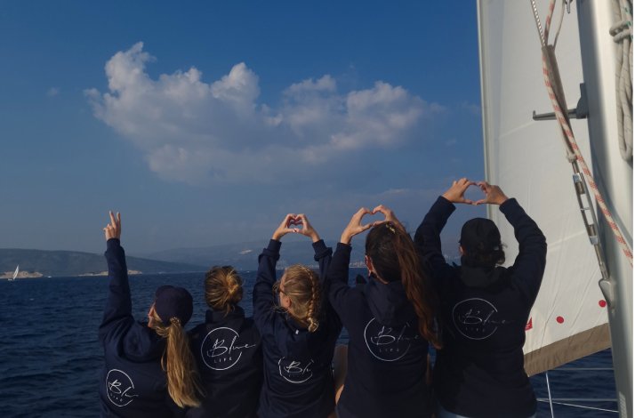 Participants of a three-day Adriatic yachting adventure showing hearts with their hands while gazing out at the sea.