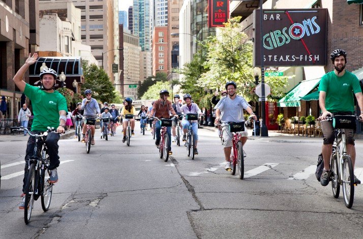A group of tourists on a bike tour of of Chicago's North Side accompanied by 2 tour guides.
