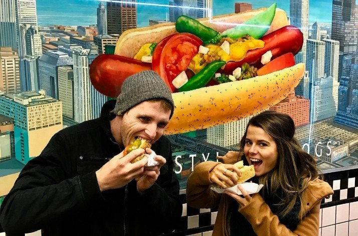 Two persons eating hotdogs 