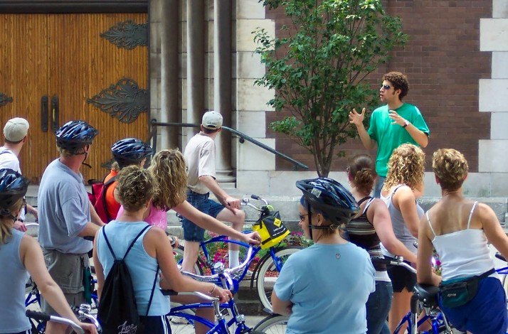 A group of tourists on bikes listening to the guide on Bobby's Bike Hike Westside Foodie Bike Tour.