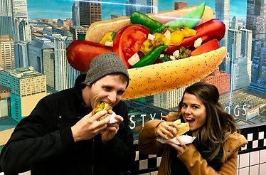 Two persons eating hotdogs 