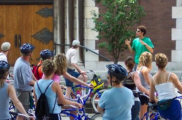 A group of tourists on bikes listening to the guide on Bobby's Bike Hike Westside Foodie Bike Tour.