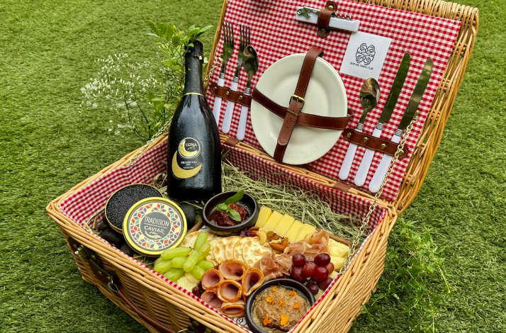 A basket of ingredients for a gourmet picnic including caviar, cheese, cold cuts, artisanal bread, and sparkling wine at Tiny Away Escape.