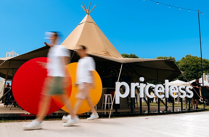 Participants pass by Mastercard priceless logo sign at the Taste of London Festival. 