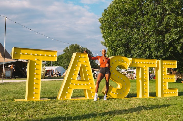 Participant poses with a 'taste' sign at the Taste of London Festival.