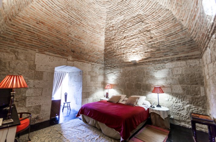 Plush double bed beneath a vaulted brick ceiling in the Tower Suite at Castillo del Buen Amor, Salamanca.