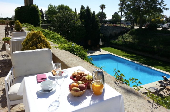 Gourmet breakfast spread on a terrace table overlooking the pool and gardens at Castillo del Buen Amor.