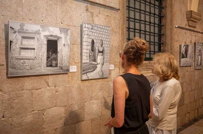 Two women viewing black-and-white photographs in an art gallery.
