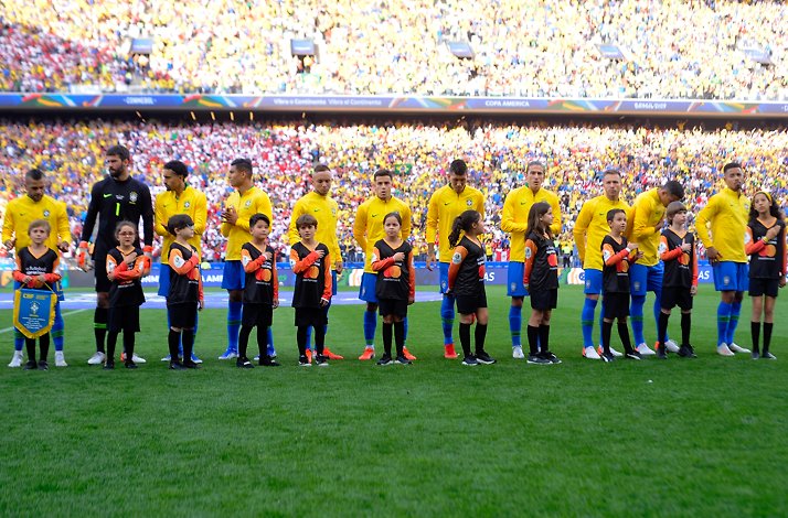 Brazil national football team and children in player mascot uniforms listening to the Peru national anthem prior to the match