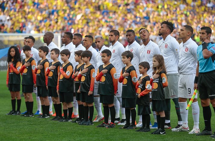 Peru national football team and children in player mascot uniforms listening to the Peru national anthem prior to the match