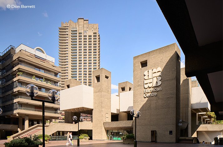 The Barbican Centre entrance plaza with its concrete brutalist architecture under a blue sky.