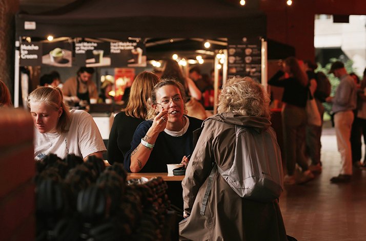 People socializing and eating at food stalls during the Barbican Outdoor Cinema event.