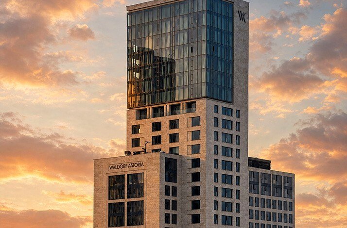 The modern high-rise exterior building facade of the Waldorf Astoria Berlin at sunset.