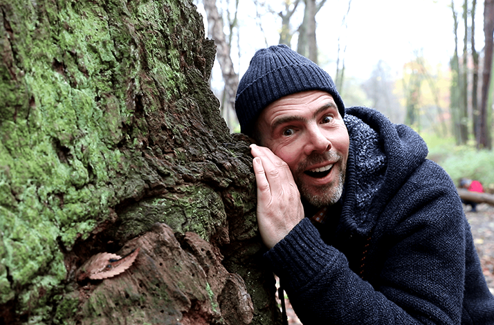 Wildlife expert Derk Ehlert peeks on a tree.