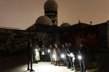 Participants with a guide having their lanterns on at a discovery tour at Teufelsberg at night.