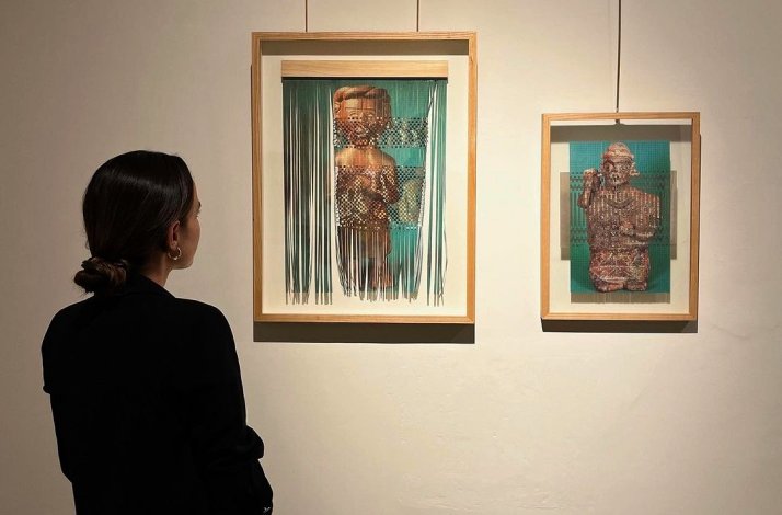 A lady observing two paintings inside the gallery