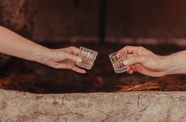 Two people during degustation, each holding a shot of Maria Bonita Mezcal