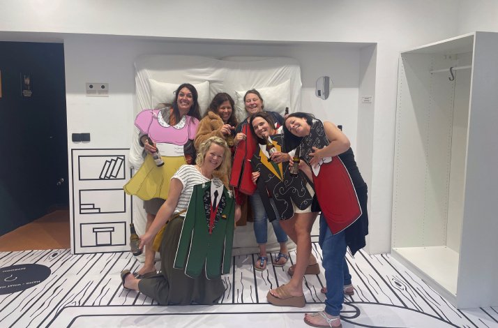 A group of people taking a picture with fake dresses made of wood at the Hangover Museum