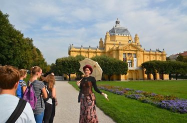 A tour guide standing in front of a castle with an umbrella on a Zagrebarium tour.