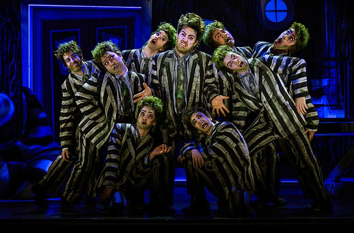 Ensemble of Beetlejuice lookalikes in signature striped suits performing theatrically