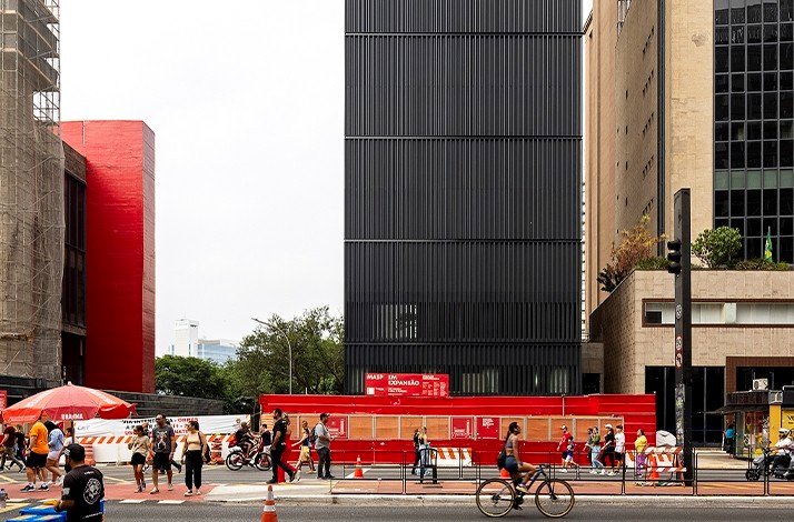 A city street scene in front of the Pietro Maria Bardi building depicts a diverse group of people traversing a crosswalk.