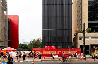 A city street scene in front of the Pietro Maria Bardi building depicts a diverse group of people traversing a crosswalk.