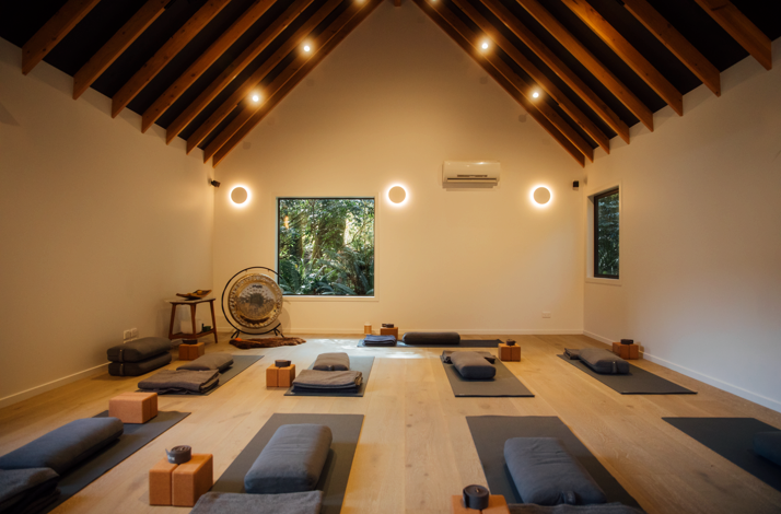 Yoga studio with mats, cushions, and a gong, surrounded by tranquil nature.