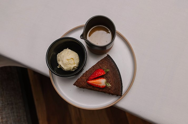 Dessert plate with chocolate cake, ice cream, and sauce, garnished with strawberries.