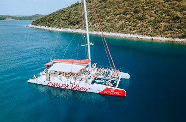A boat with the Summer blues logo on its board sailing in the costal waters with tourists aboard.