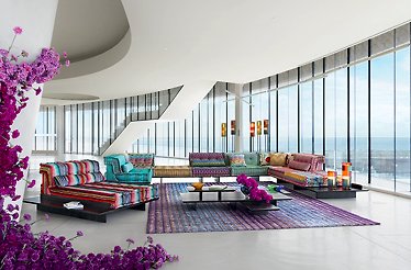 Roche Bobois showroom with multiple couches of various colours, coffee table and purple carpet.