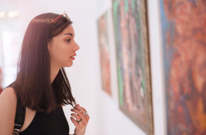A girl is looking at paintings displayed in the art gallery 