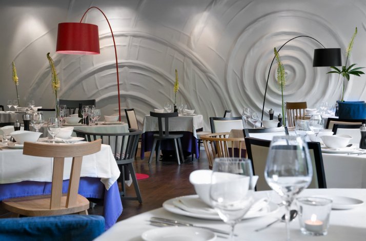 Dubravkin put's dining room interior with white sculpted walls, arc floor lamps, and formally set tables with stemware.