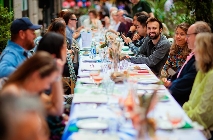 Group dining at a long table decorated with flowers and food.