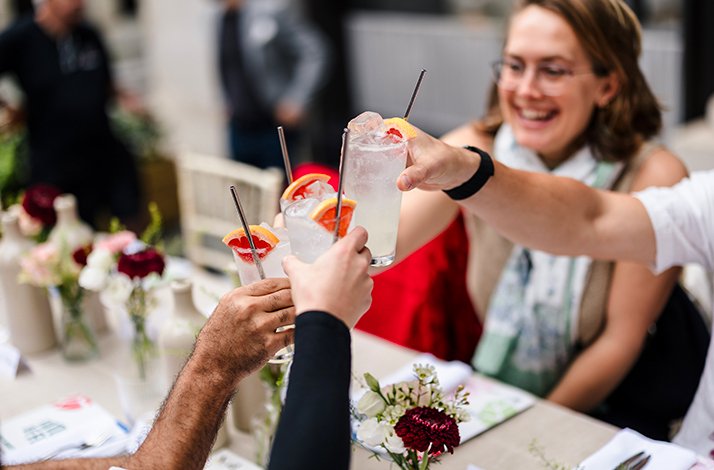 People toasting with cocktails at a decorated table.
